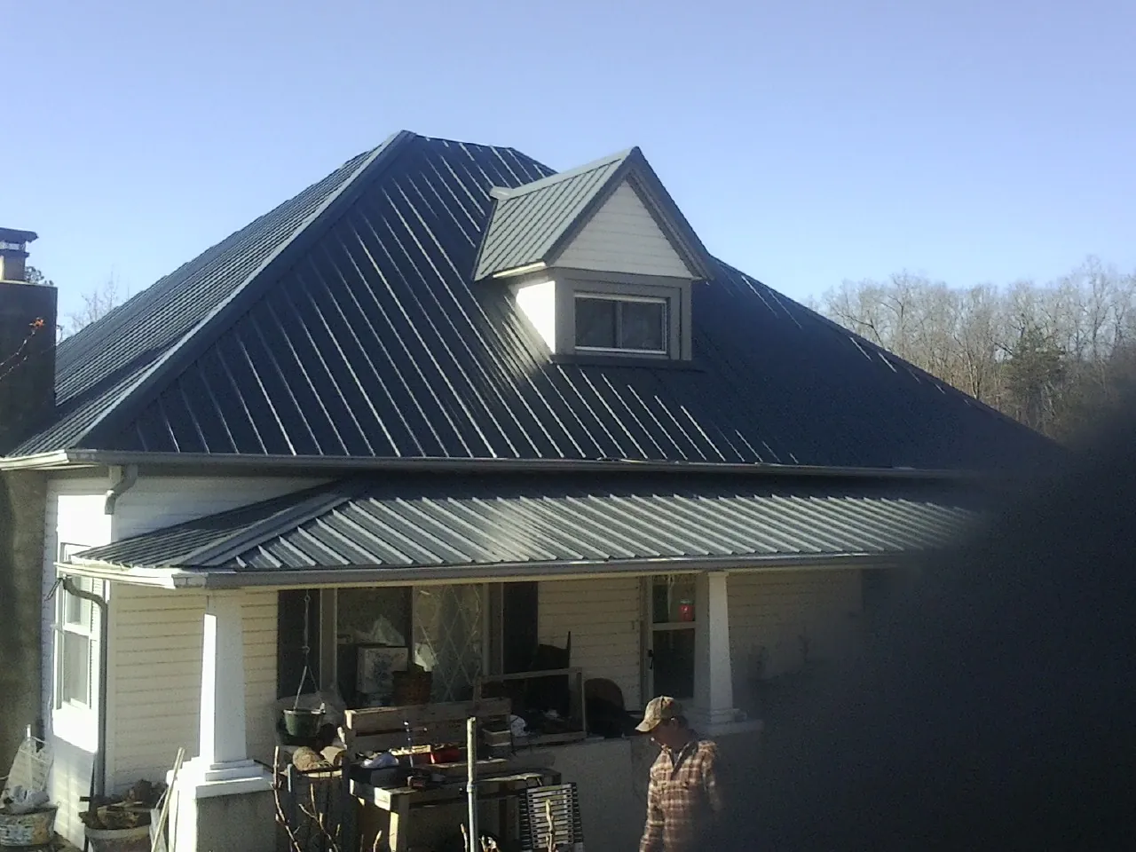 Dark blue standing seam metal roof with a dormer above a front porch in Bloomington